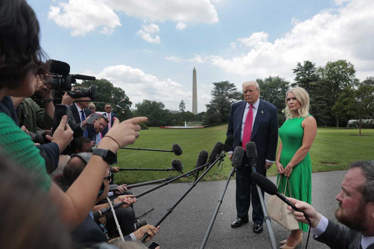 Donald Trump and Karoline Leavitt stand outside the White House taking questions from reporters.
