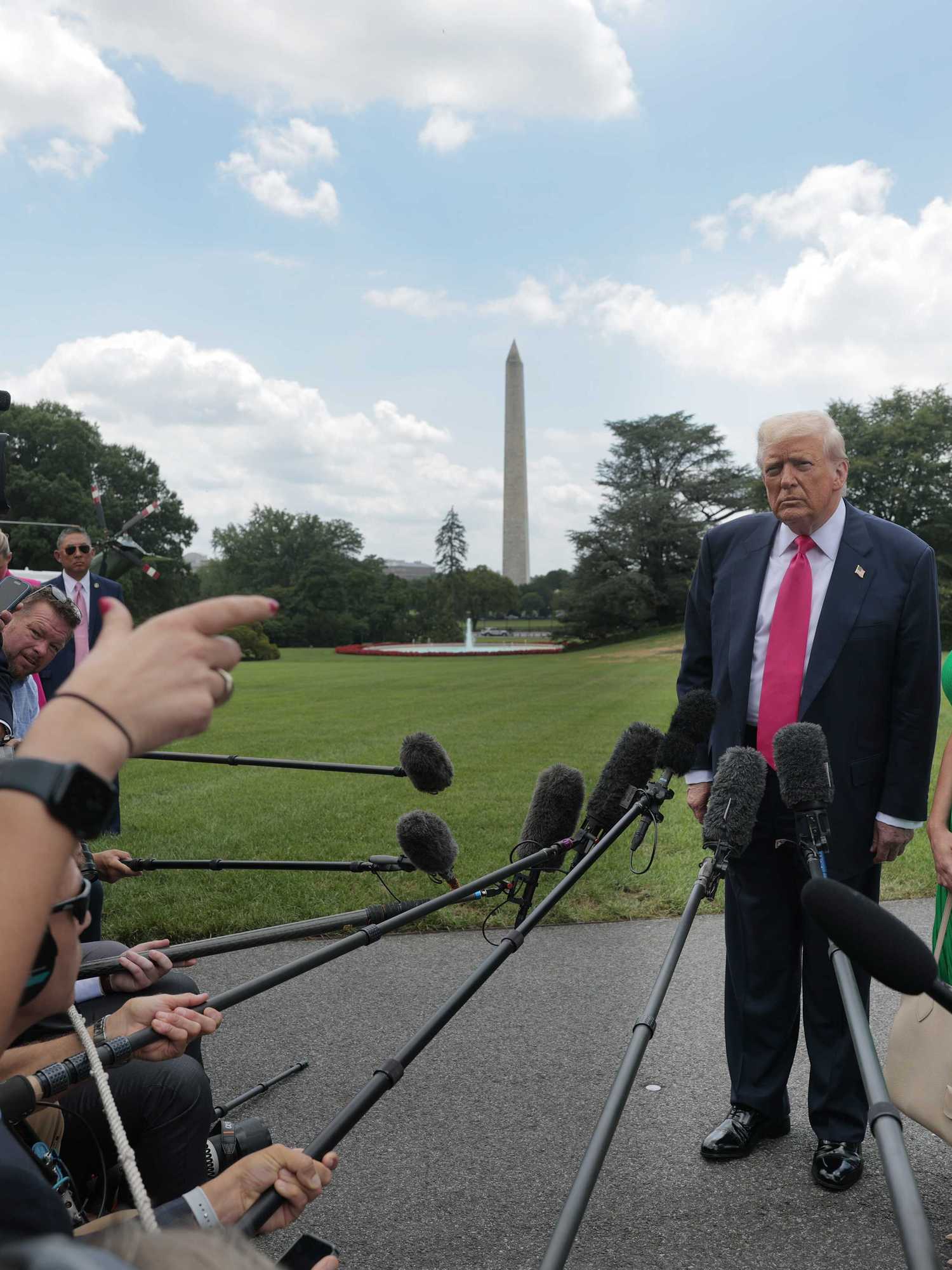 Donald Trump and Karoline Leavitt stand outside the White House taking questions from reporters.