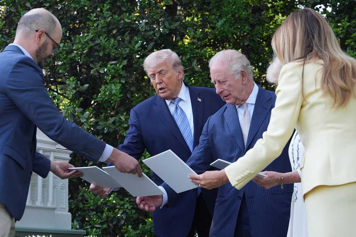 Donald Trump and King Charles III look at white cards at the White House beehives.