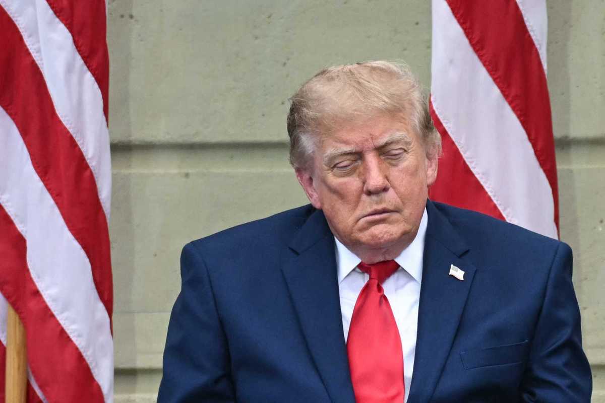 Donald Trump appears to fall asleep while sitting in front of two American flags.