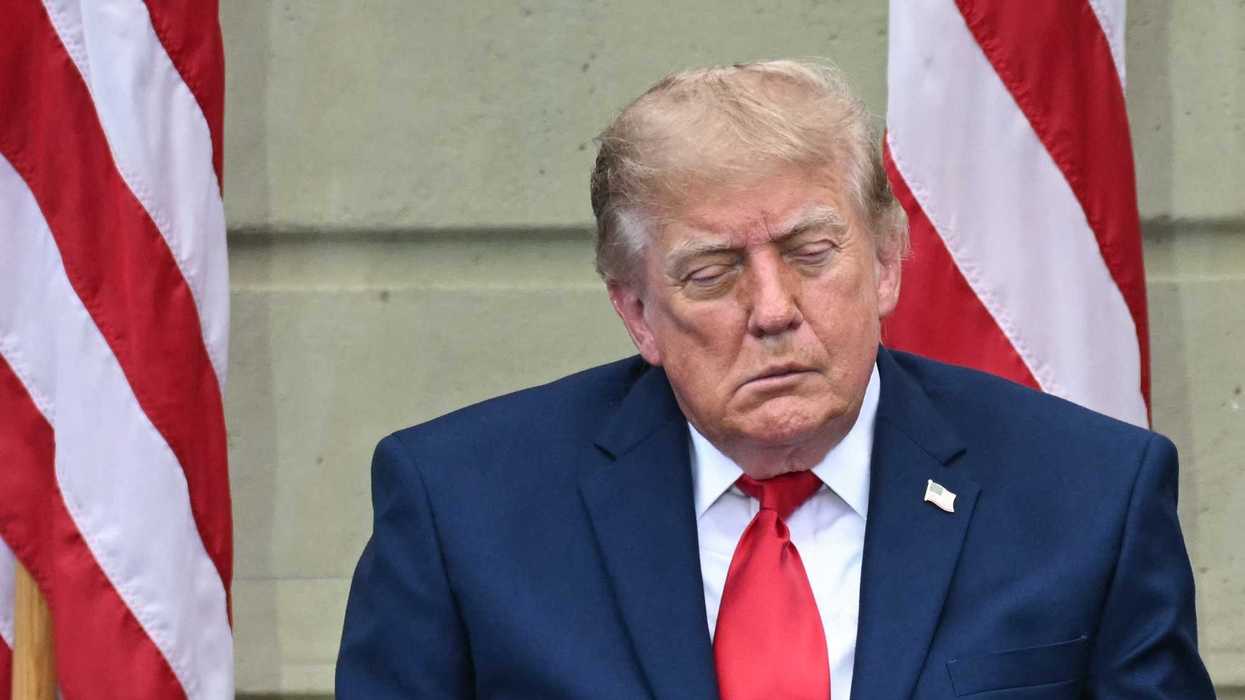 Donald Trump appears to fall asleep while sitting in front of two American flags.