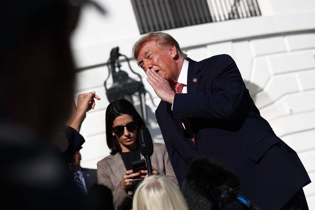 Donald Trump covers one side of his mouth as he talks to reporters outside the White House.
