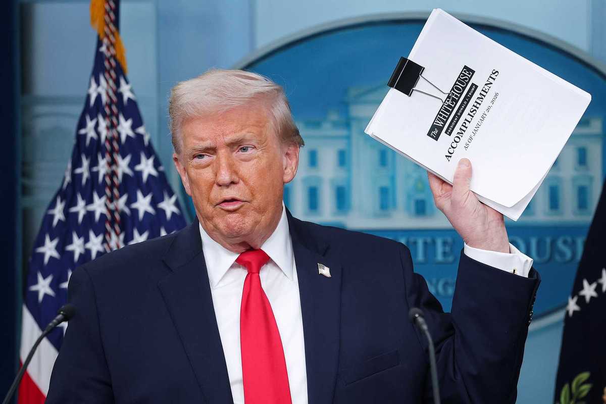 Donald Trump displays a stack of papers labeled 'The White House Accomplishments' during a press briefing in the James S. Brady Press Briefing Room of the White House.