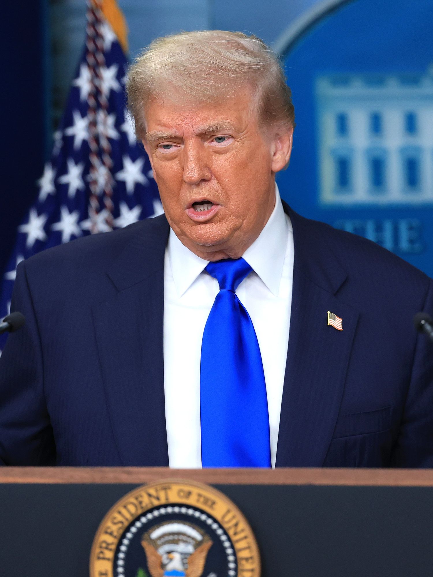 Donald Trump gestures with his hands as he speaks to the press behind his presidential lectern in the White House.