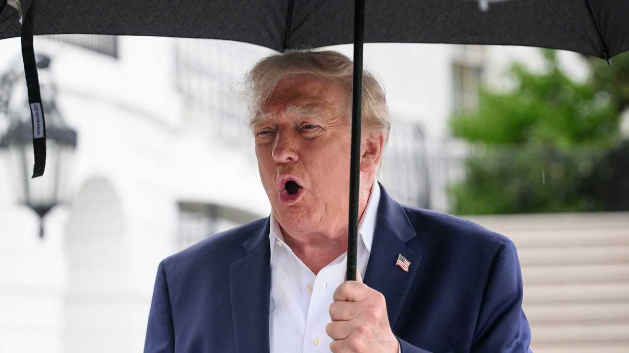 Donald Trump holding an umbrella and speaking to reporters outside the White House.