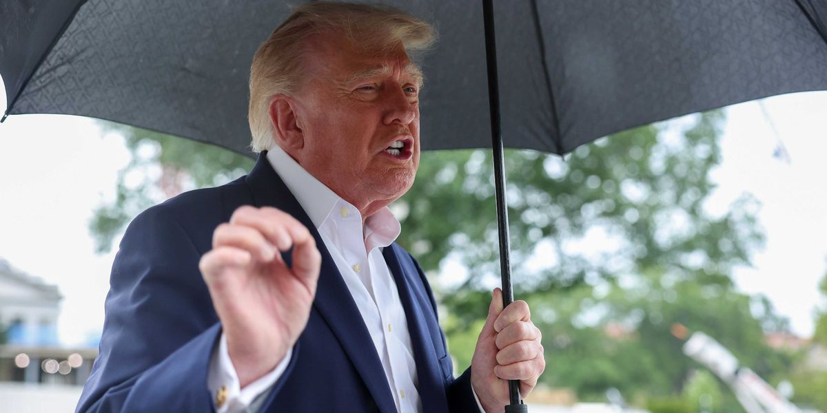 Donald Trump holding an umbrella and speaking to reporters outside the White House.