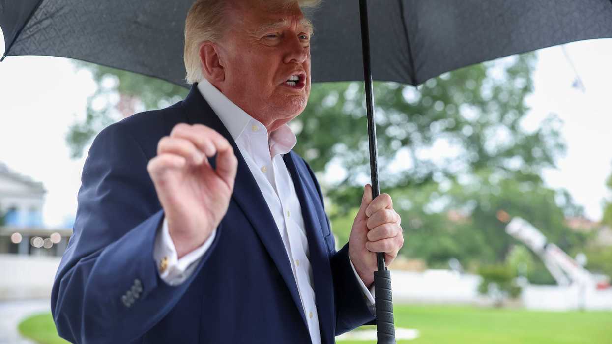 Donald Trump holding an umbrella and speaking to reporters outside the White House.