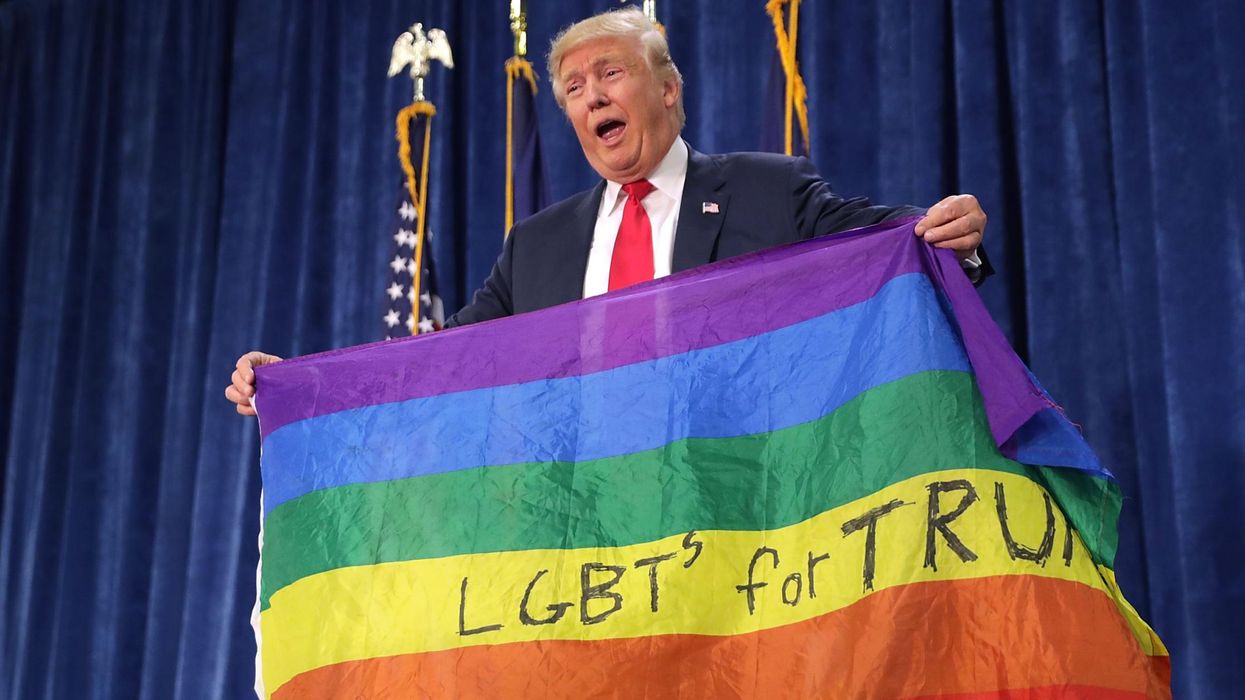 Donald Trump holds an LGBT+ rainbow flag during a campaign rally in 2016