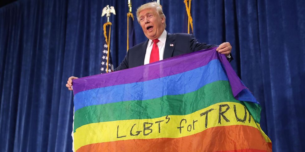 Donald Trump holds an LGBT+ rainbow flag during a campaign rally in 2016