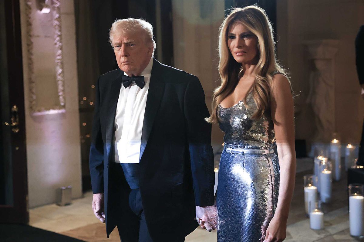 Donald Trump in a black suit and bow tie holds the hand of Melania Trump, in a silver dress, at Mar-a-Lago.