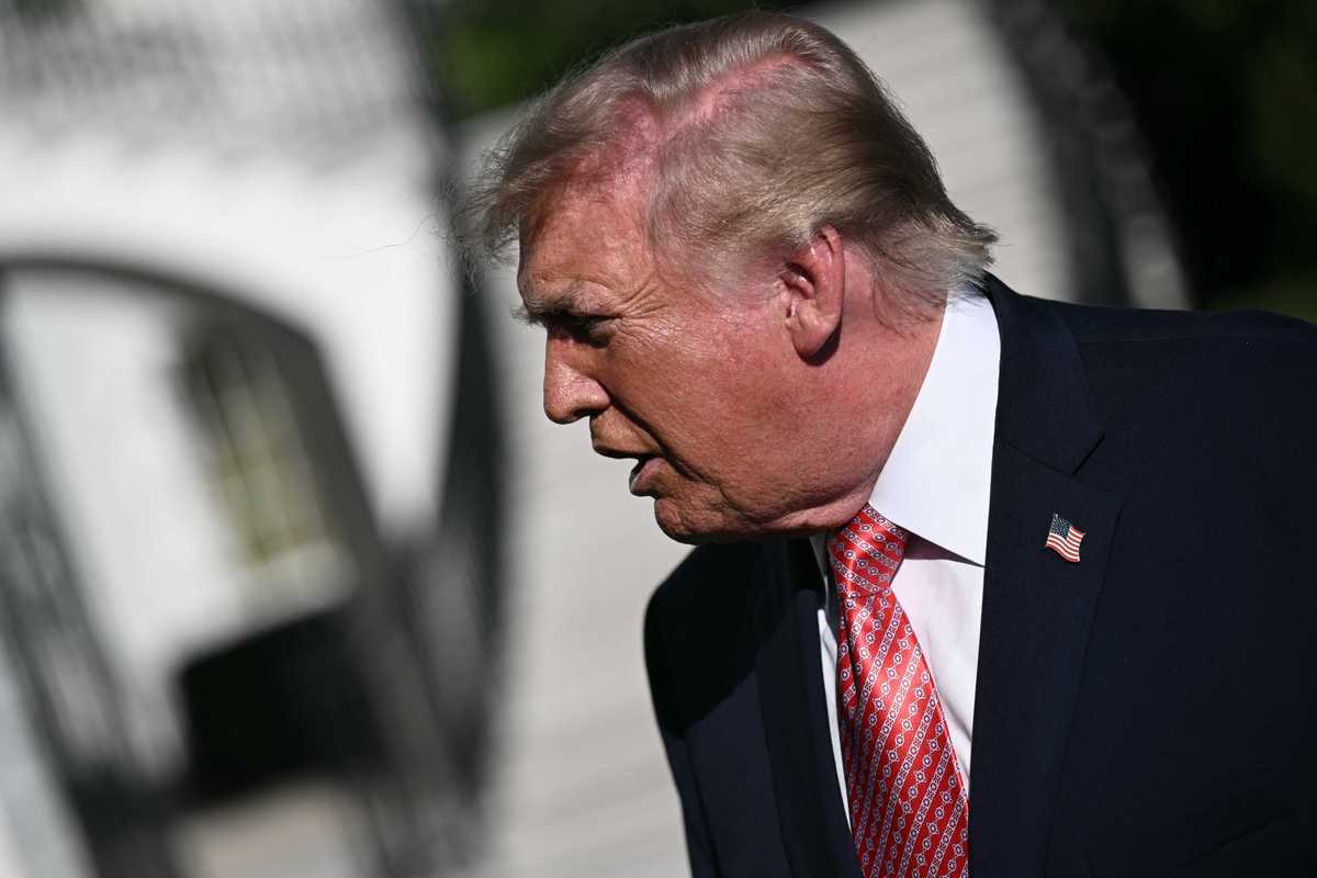 Donald Trump, in a black suit, speaks to reporters outside the White House.