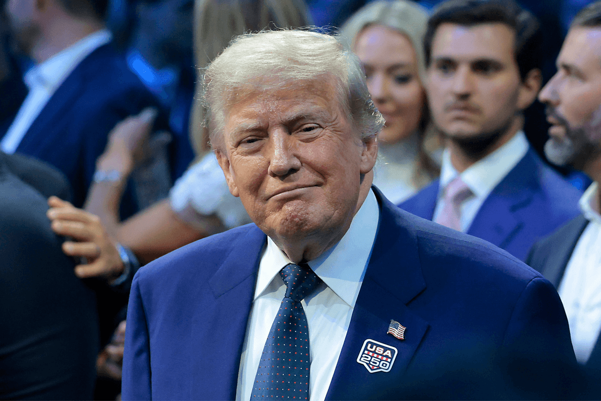 Donald Trump in a blue suit smiles as he attends the UFC Freedom 250 event.