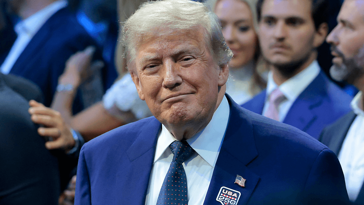 Donald Trump in a blue suit smiles as he attends the UFC Freedom 250 event.