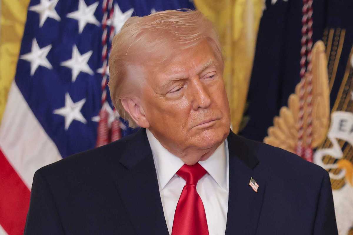 Donald Trump in a blue suit tilts his head slightly to the right as he looks to the left, with a neutral expression on his face.