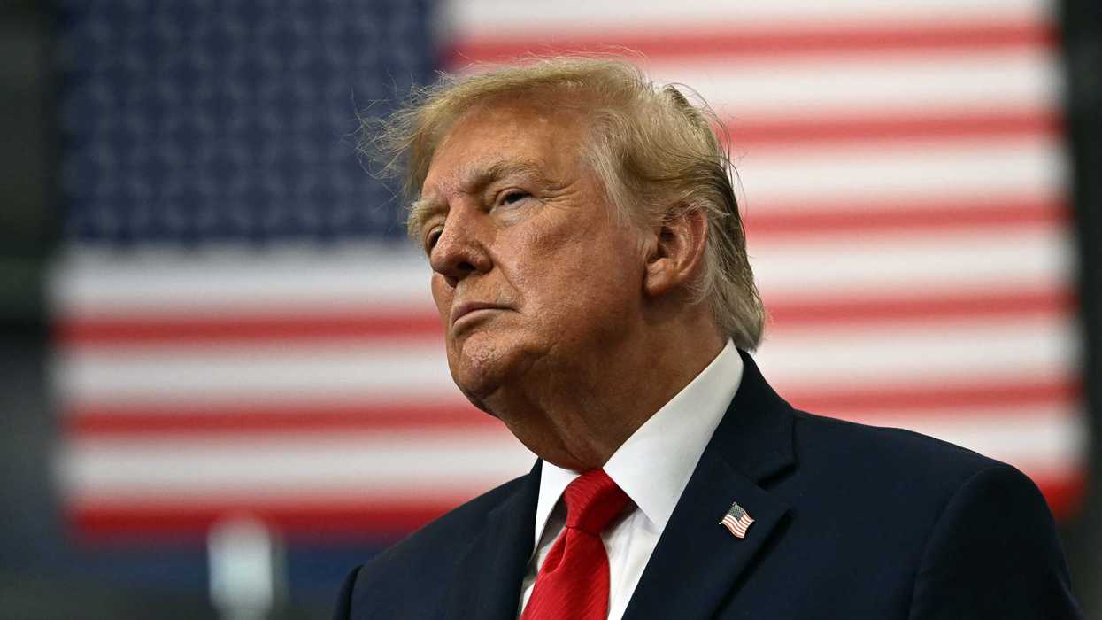 Donald Trump in front of a US flag out of focus in the background.