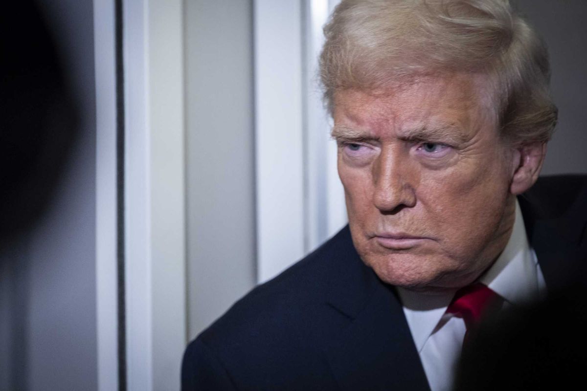 Donald Trump in the hallway of Air Force One taking questions from reporters.