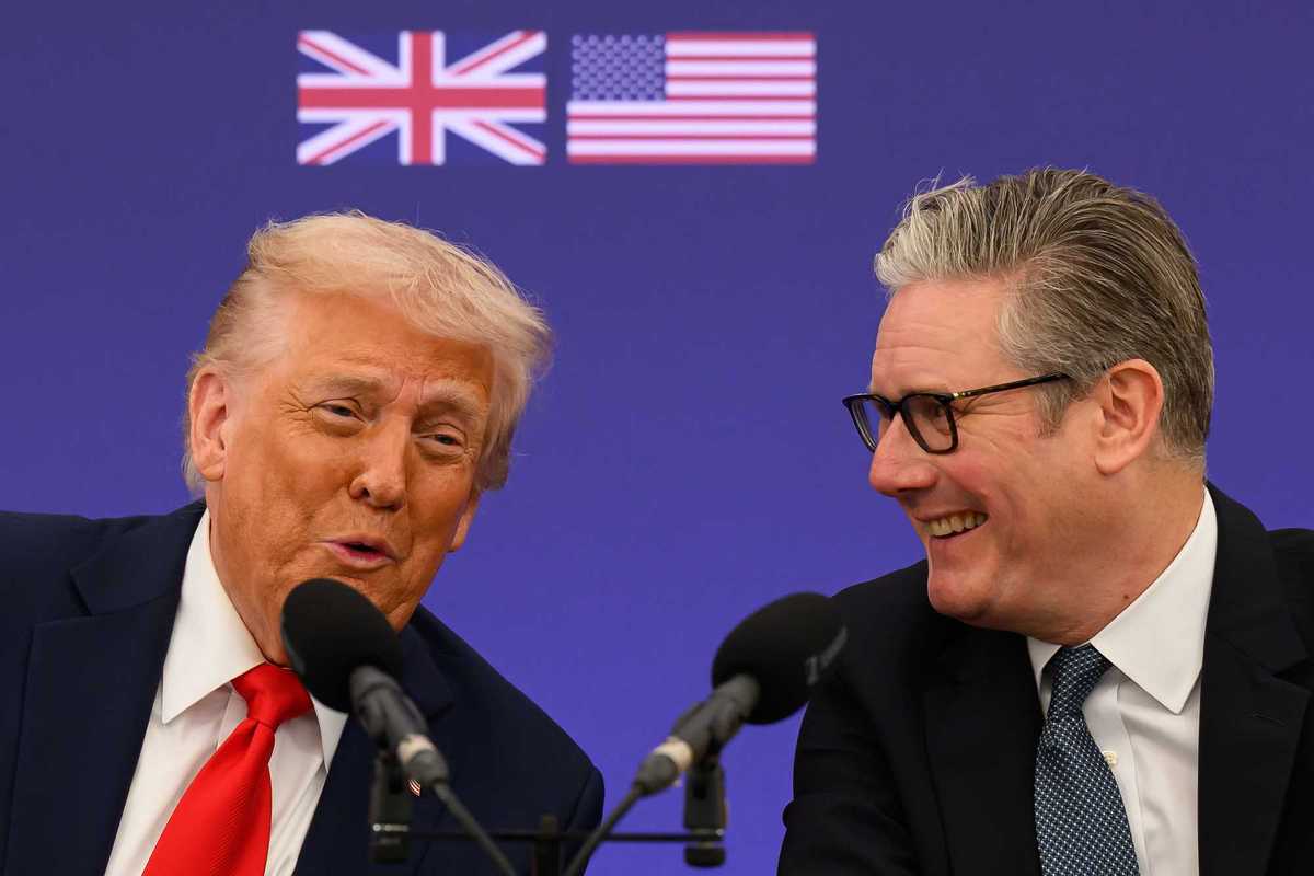 Donald Trump, left, and Keir Starmer, right as they speak into microphones in front of them. The UK and US flags are seen on a blue poster board behind them.