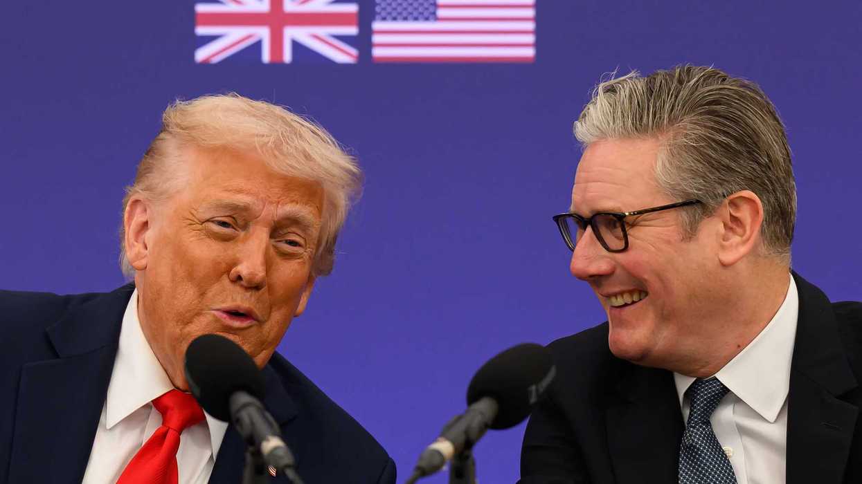Donald Trump, left, and Keir Starmer, right as they speak into microphones in front of them. The UK and US flags are seen on a blue poster board behind them.