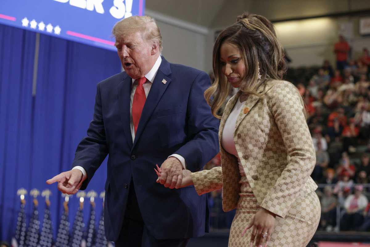 Donald Trump, left, and Nicki Minaj, right, hold hands as they walk down steps at a rally in Michigan.