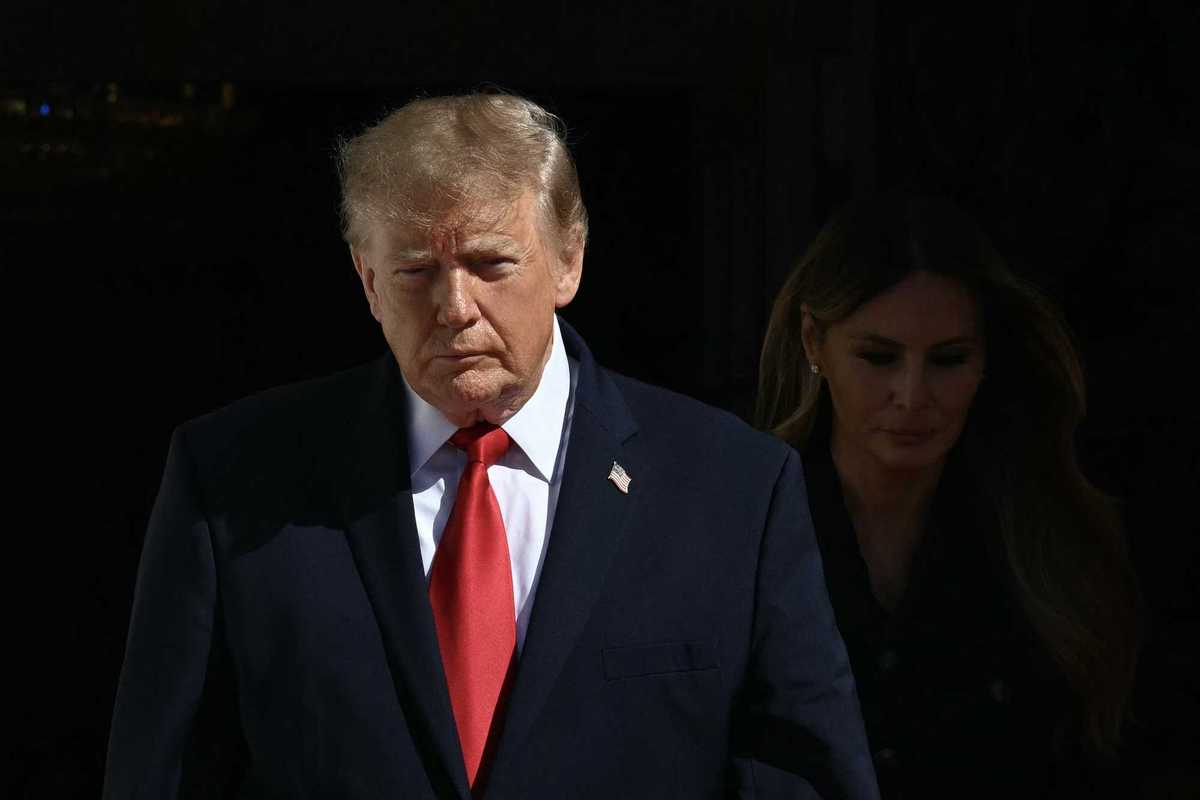 Donald Trump, left, in a black suit with a red tie. Right, barely lit, is Melania Trump.