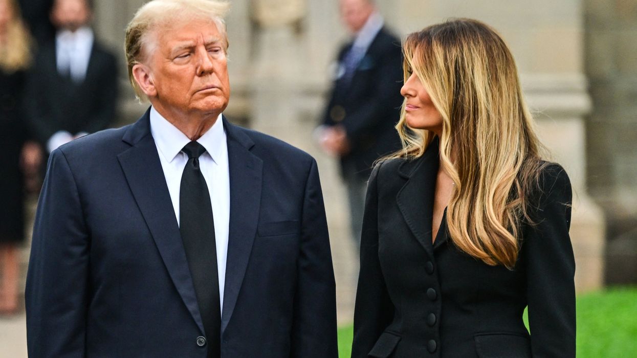 Donald Trump, left, looks ahead with a frowning facial expression, while Melania, right, with wavy blonde hair, turns her head right to look at him with a faint smile.