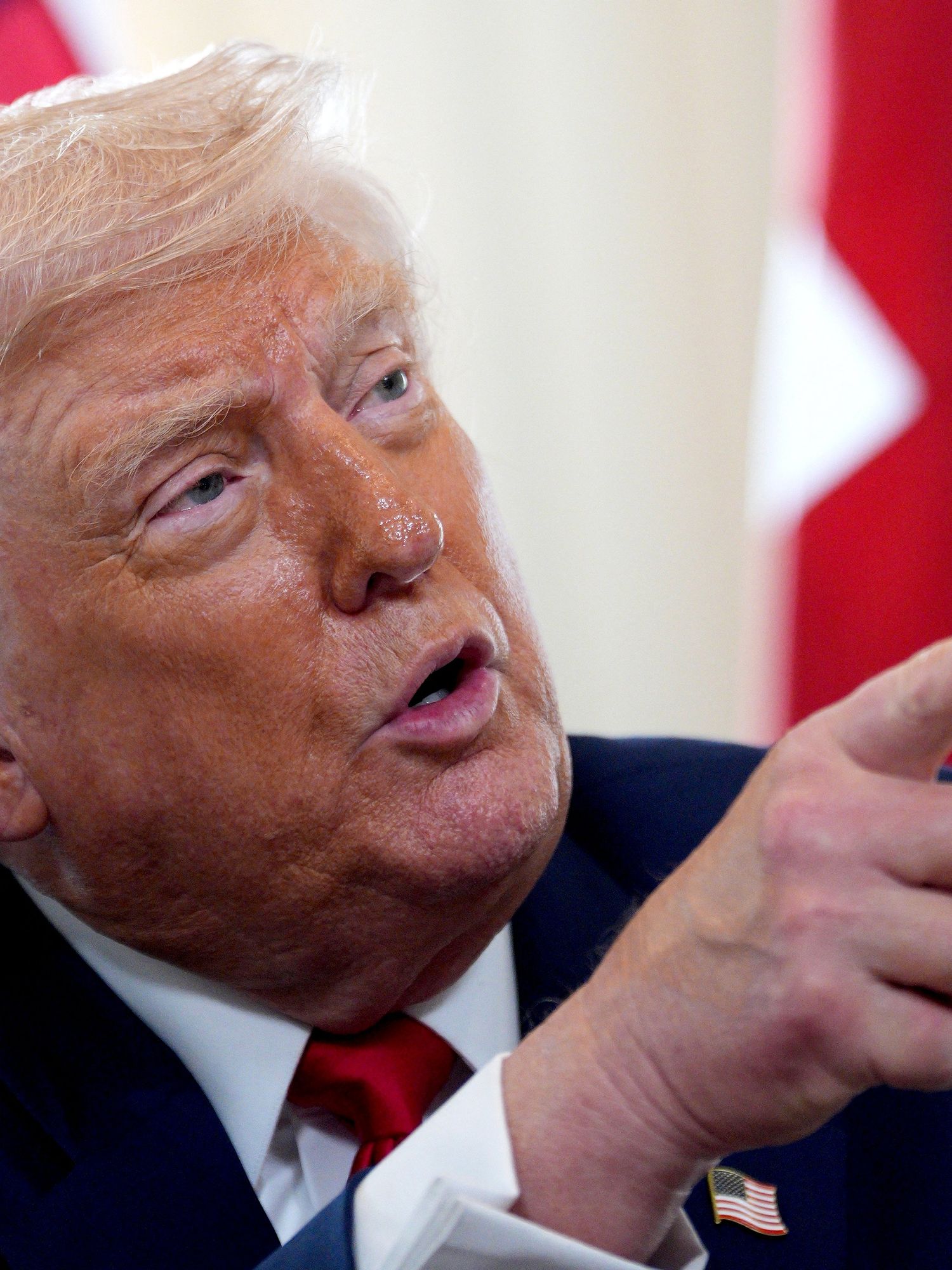 Donald Trump looking to his left and pointing at someone off-camera. He's taking questions from the media.