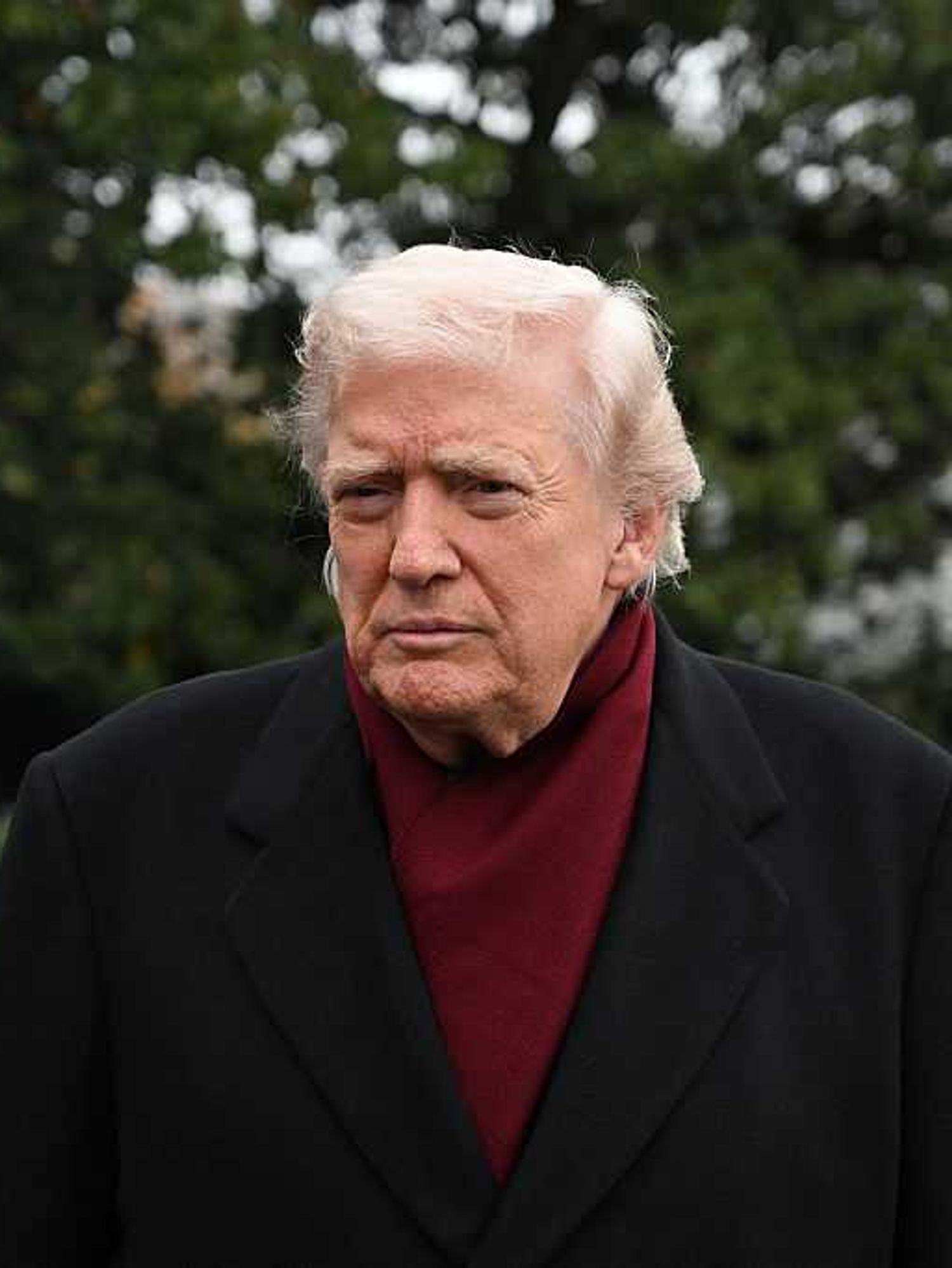 Donald Trump outside the White House, wearing burgundy underneath a black coat.