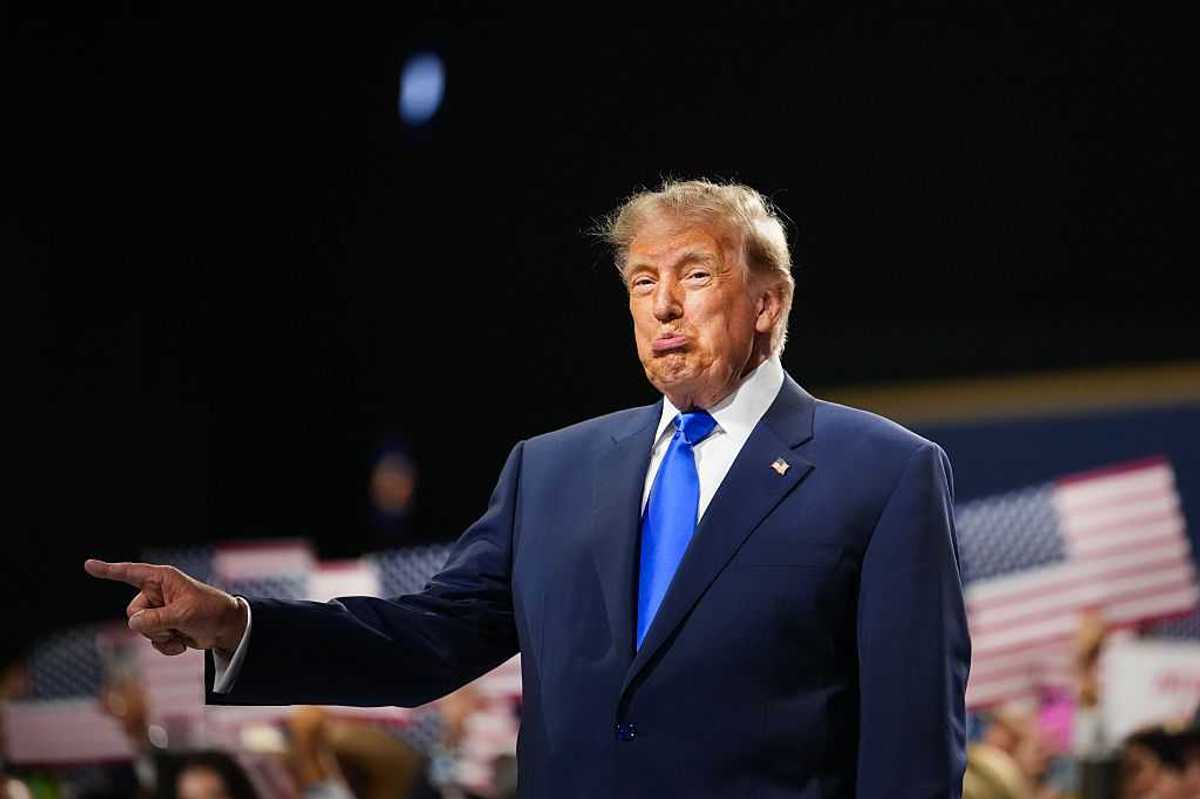 Donald Trump pointing at something off-stage with his right hand, and his bottom lip pushed out.
