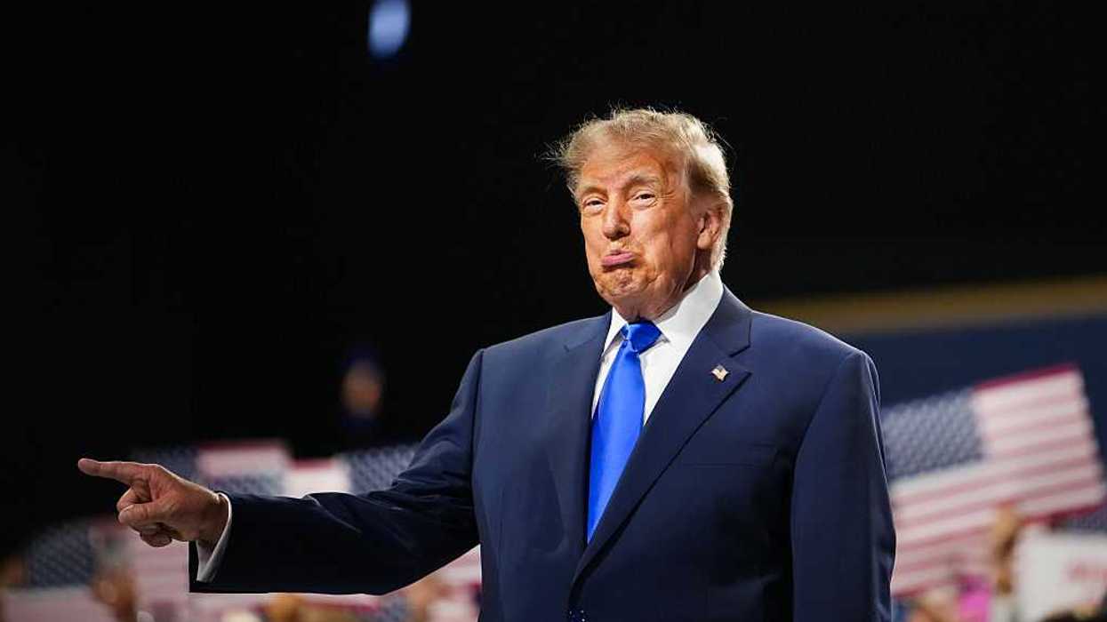 Donald Trump pointing at something off-stage with his right hand, and his bottom lip pushed out.