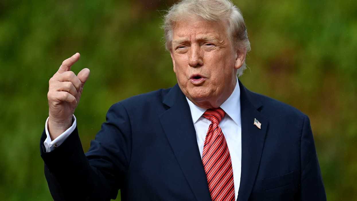 Donald Trump pointing with his right hand while speaking to reporters.
