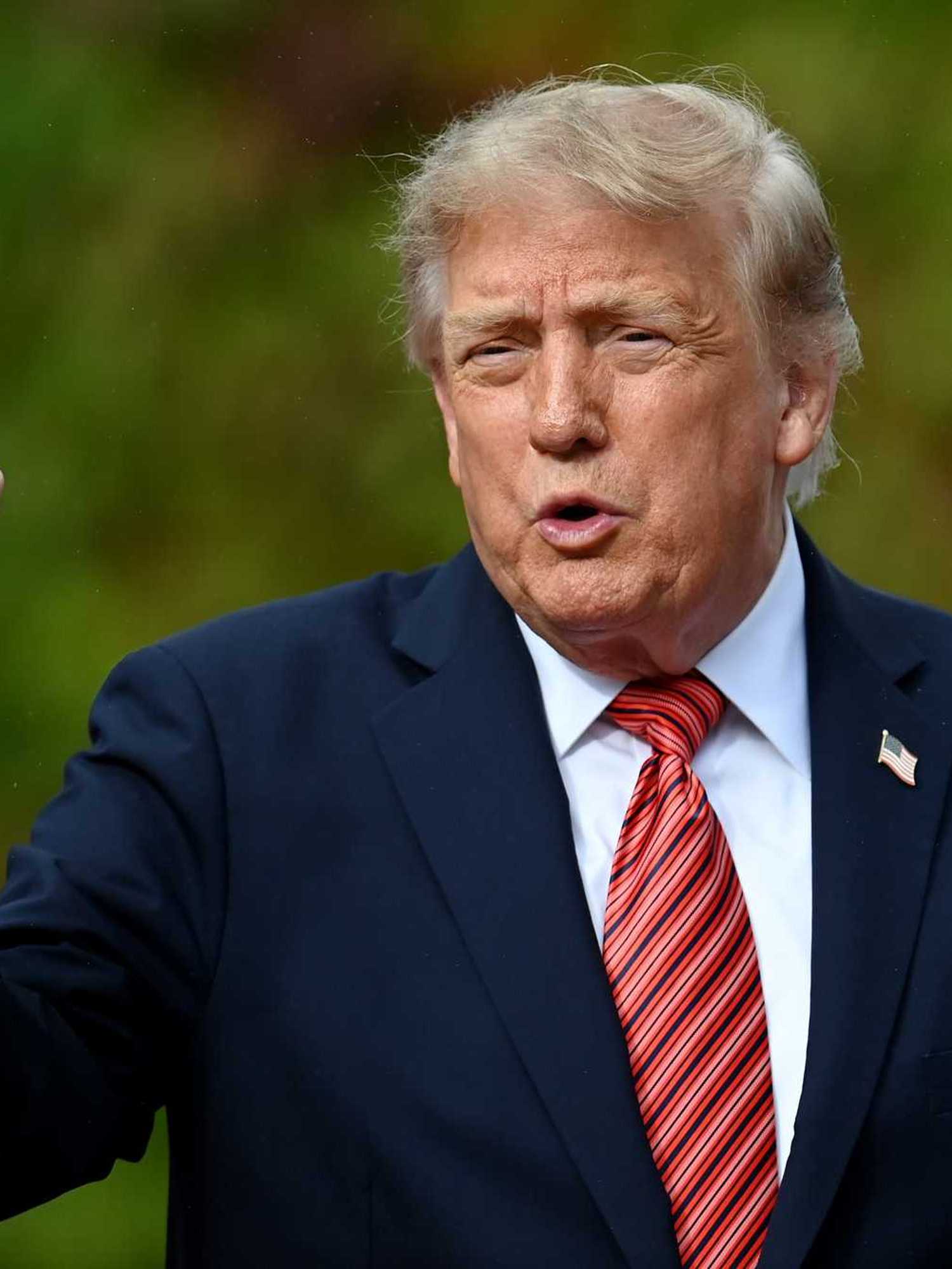 Donald Trump pointing with his right hand while speaking to reporters.