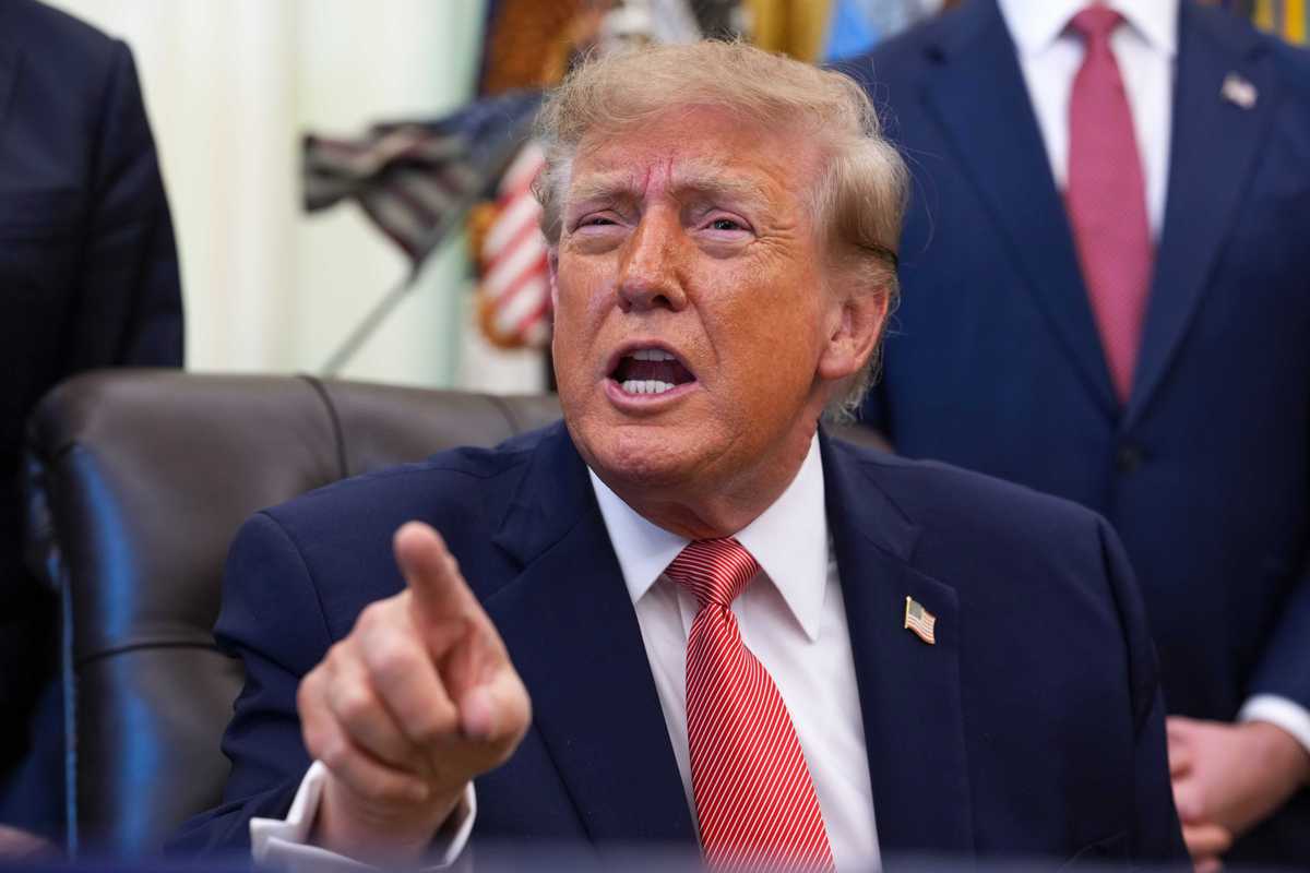 Donald Trump points and talks to a reporter from behind the Resolute Desk in the Oval Office.
