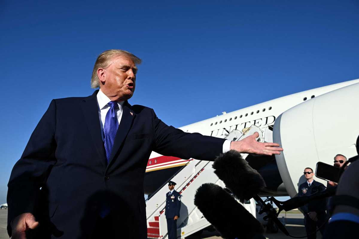 Donald Trump points at a reporter on an airfield, with Air Force One visible behind him.