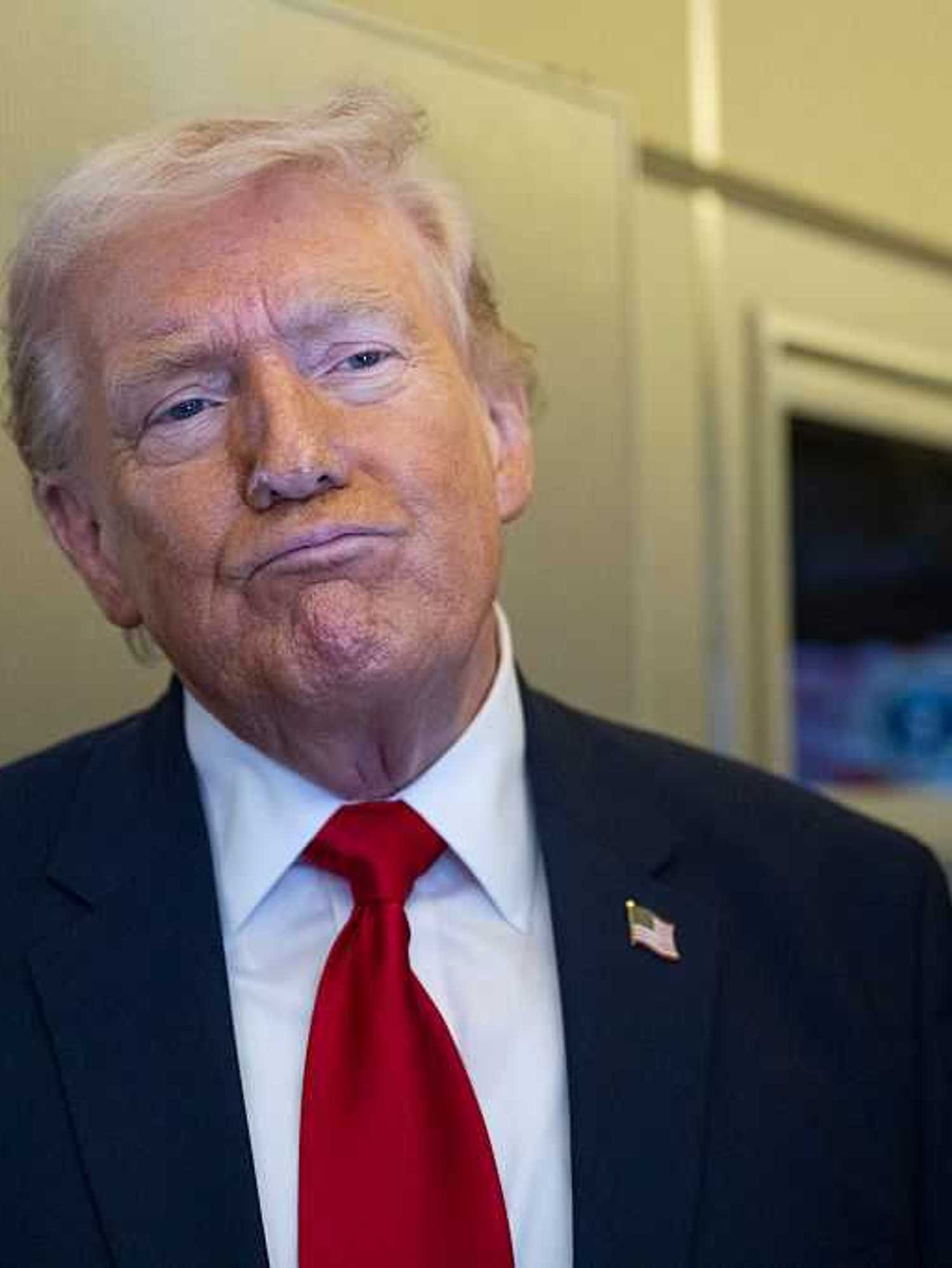 Donald Trump pouts his lips in thought while speaking to reporters on board Air Force One.