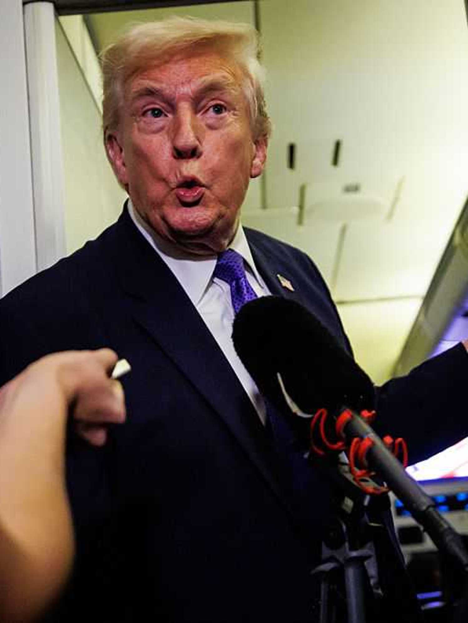Donald Trump purses his lips in shock as he is interviewed by reporters on board Air Force One.