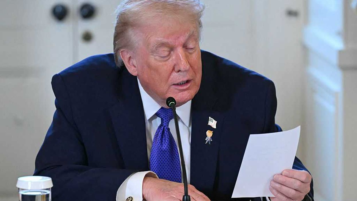 Donald Trump reads from a note on a piece of paper during a White House meeting.