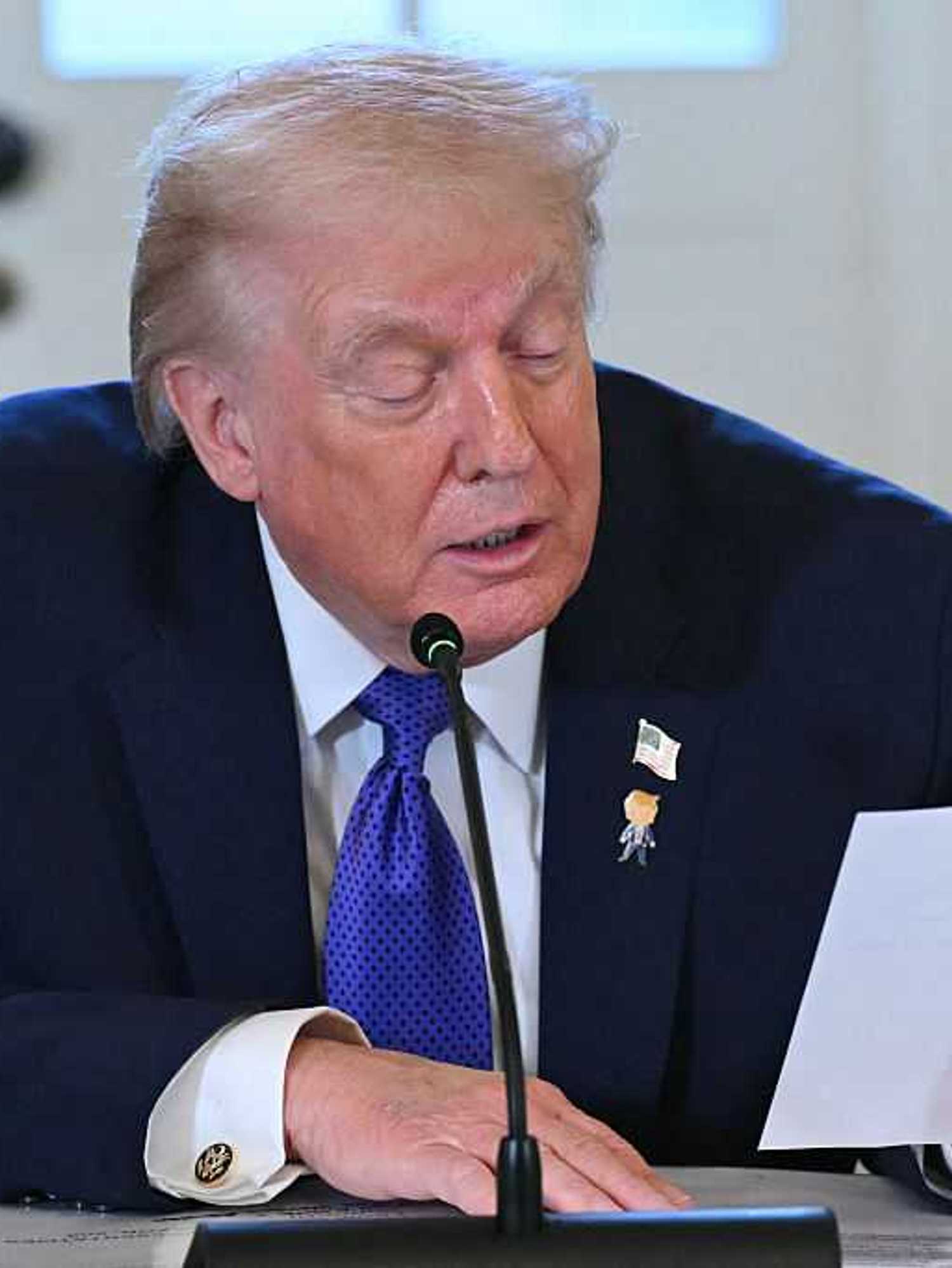 Donald Trump reads from a note on a piece of paper during a White House meeting.
