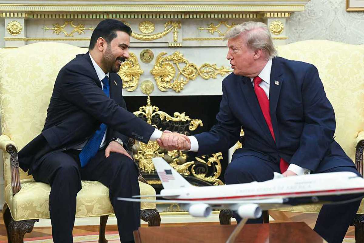 Donald Trump, right, shakes hands with Ali al-Zaidi, left, in front of the fireplace in the Oval Office.