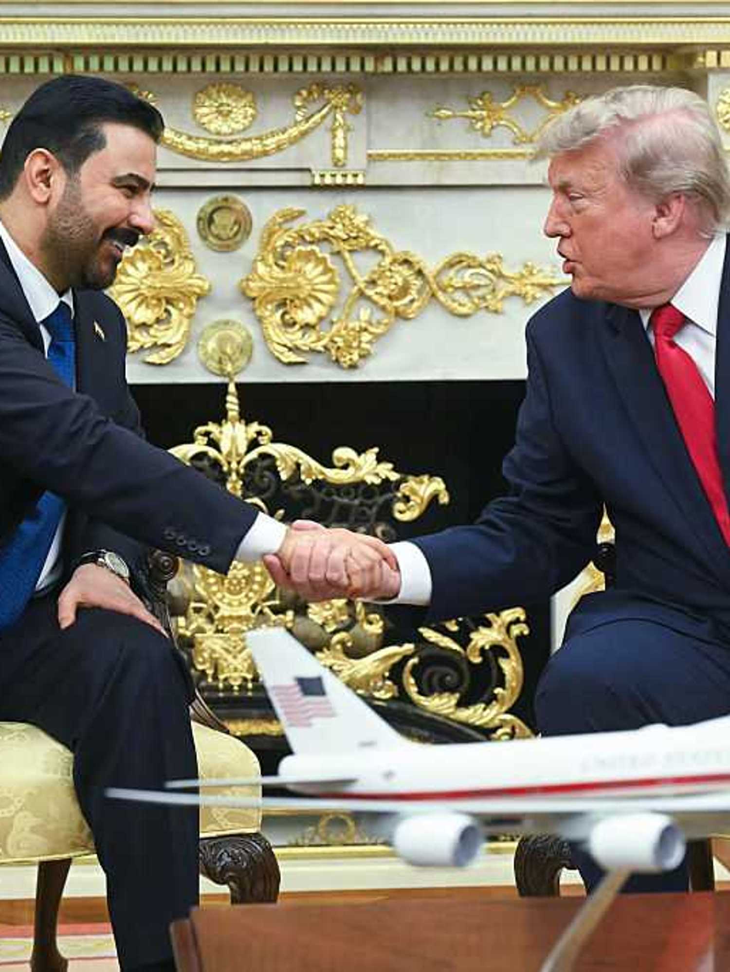 Donald Trump, right, shakes hands with Ali al-Zaidi, left, in front of the fireplace in the Oval Office.