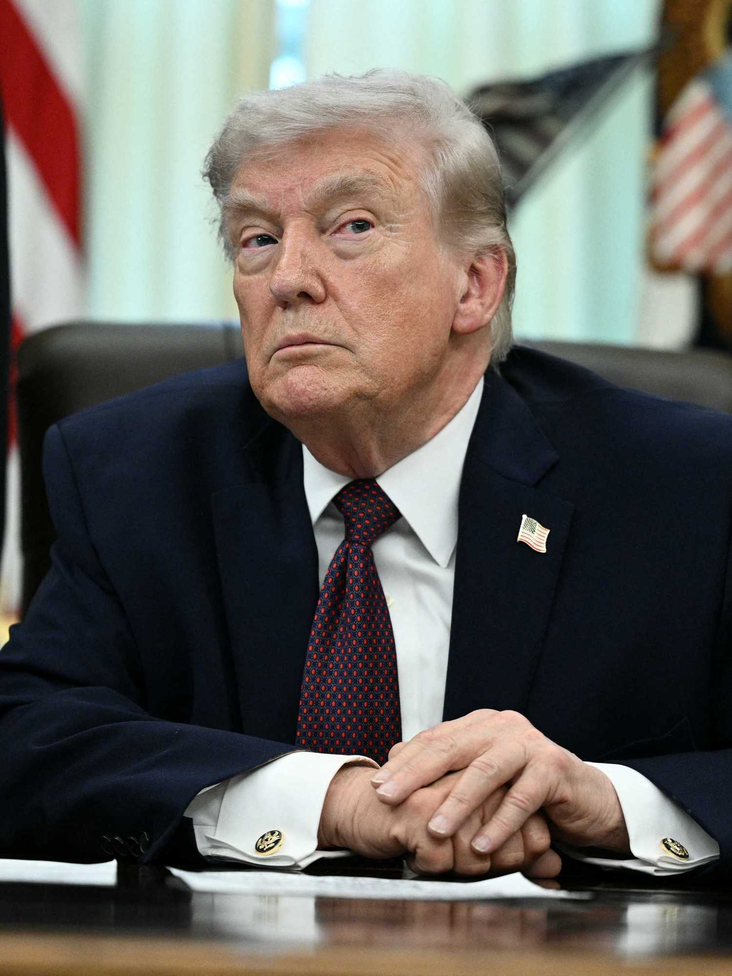 Donald Trump sits behind the Resolute Desk in the Oval Office.