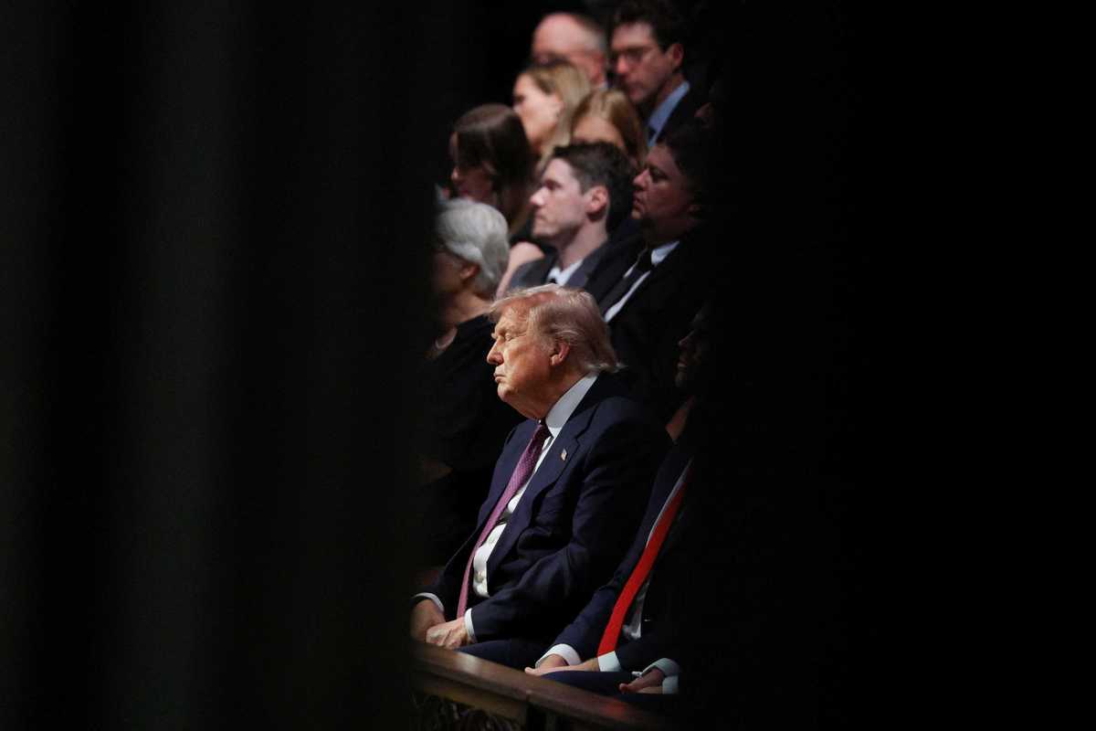 Donald Trump sits in wooden seating at the funeral for Lindsey Graham, with his eyes closed.