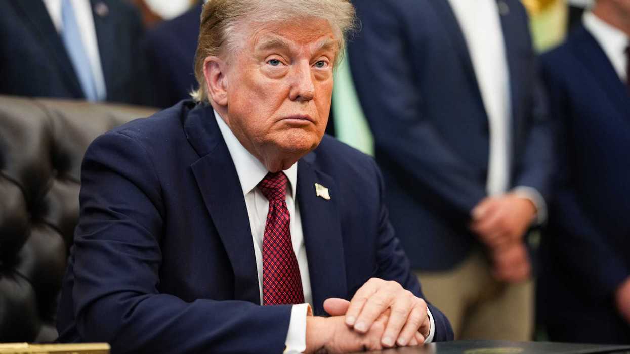 Donald Trump sitting at the Resolute Desk in the Oval Office of the White House.
