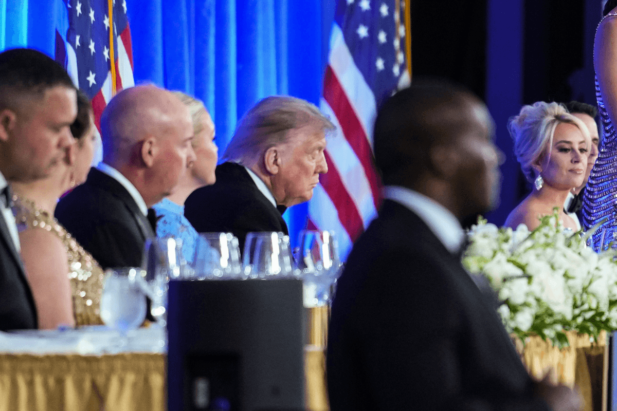 Donald Trump sitting behind a table at the White House Correspondents' Dinner, seemingly with his eyes closed.