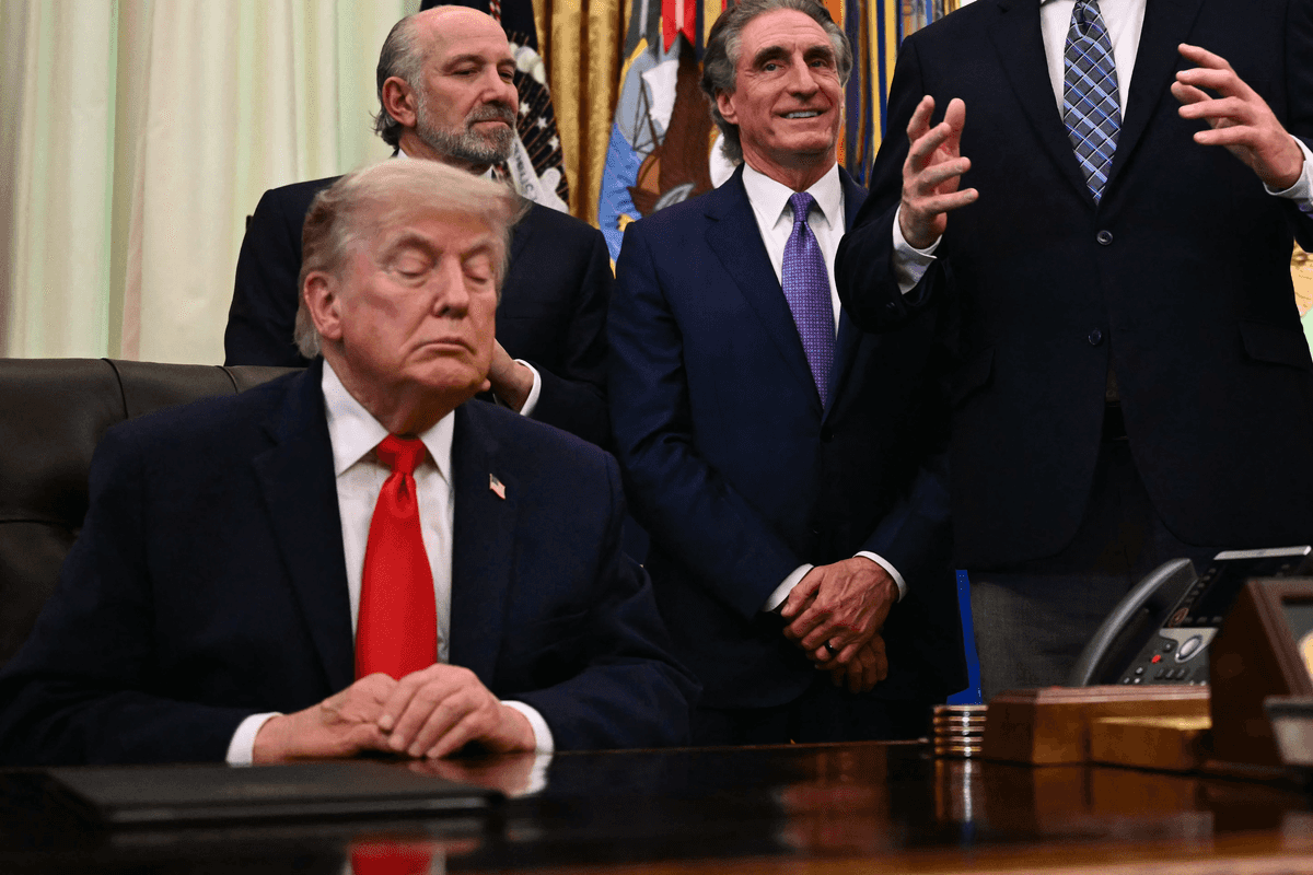 Donald Trump sitting behind the Resolute Desk in the Oval Office, appearing to have his eyes closed.