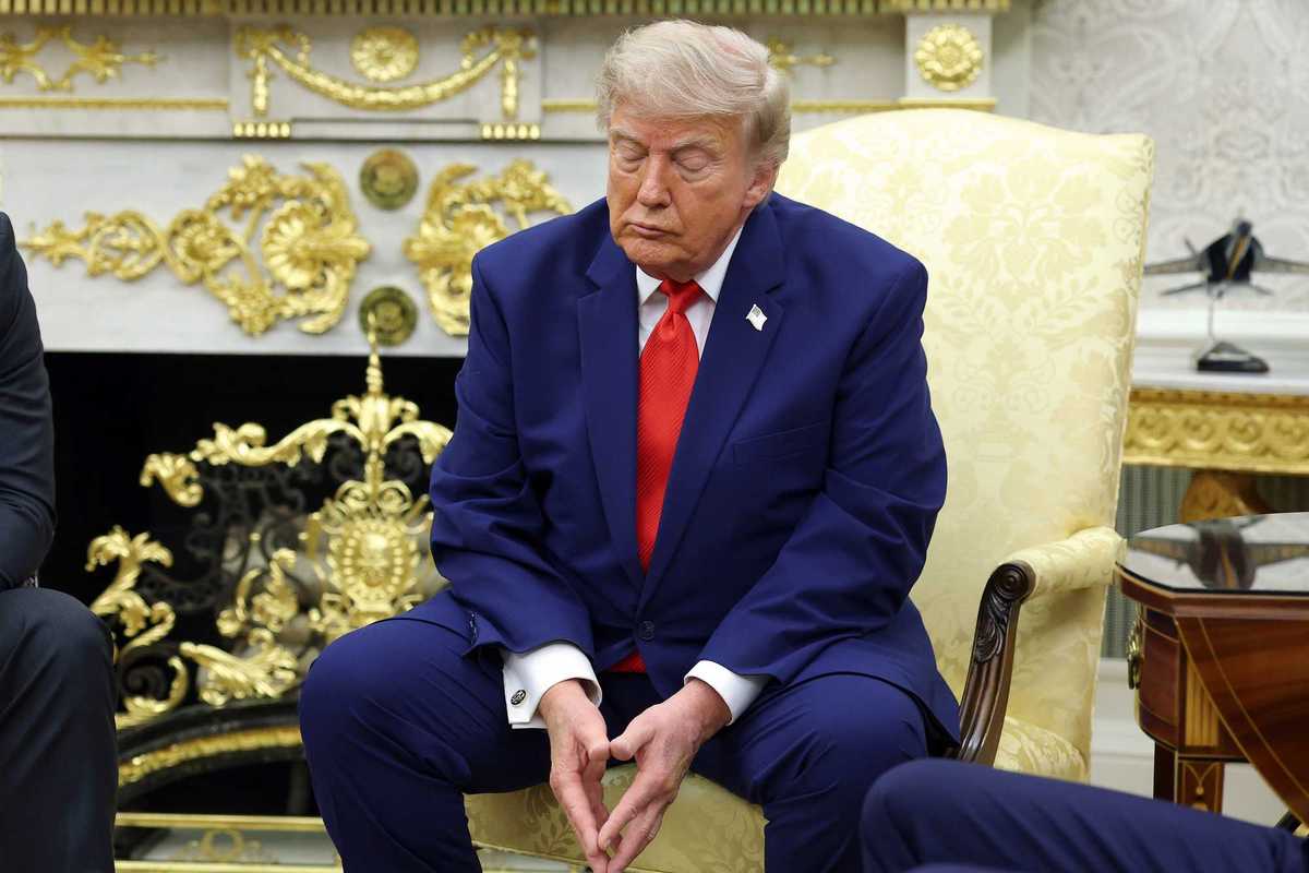 Donald Trump sitting in a cream chair in the Oval Office, with his eyes closed.