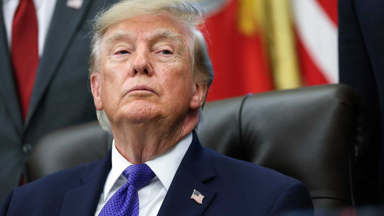 Donald Trump sitting upright in his chair behind the Resolute Desk in the Oval Office.