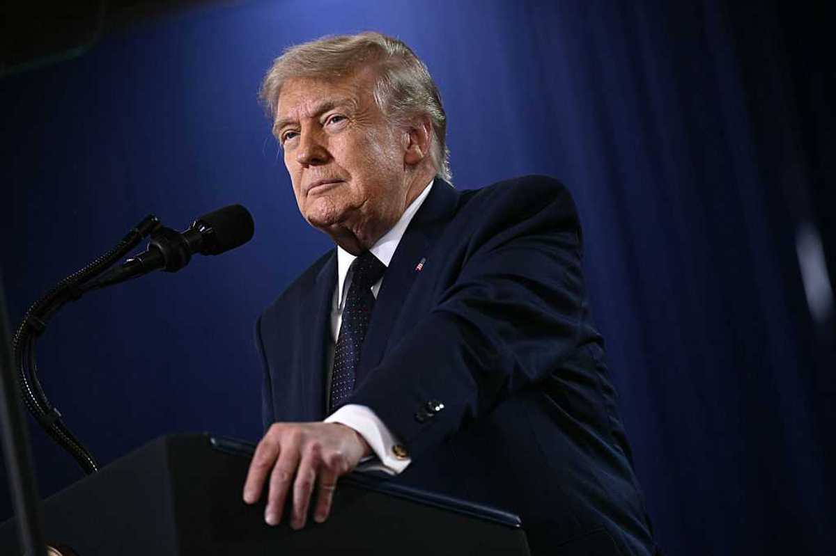 Donald Trump smiles as he speaks behind a black lectern.