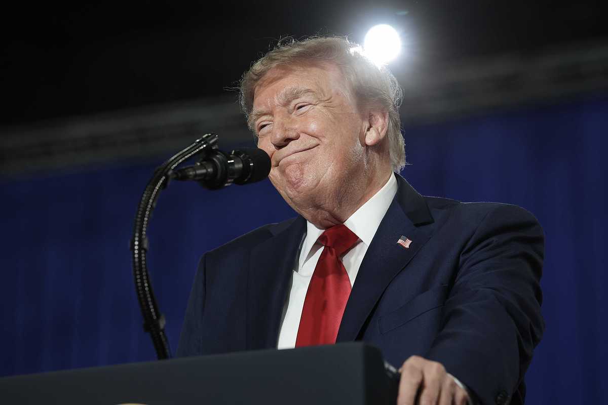 Donald Trump smiles as he stands behind his blue presidential lectern.