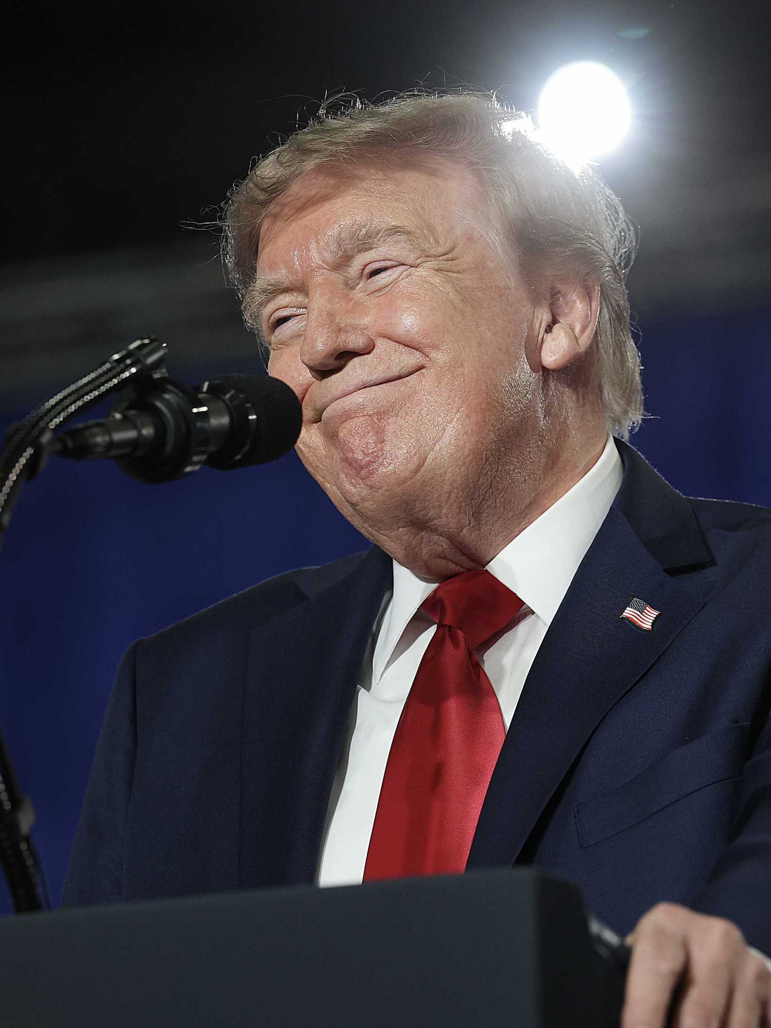 Donald Trump smiles as he stands behind his blue presidential lectern.