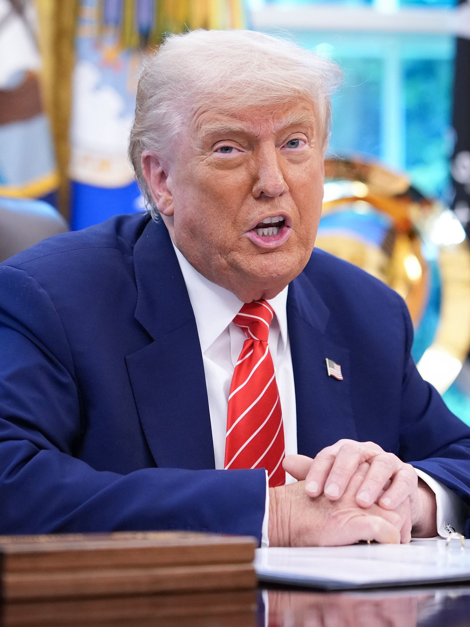 Donald Trump speaks to press sat behind his desk in the Oval Office.